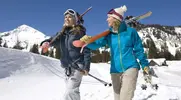 Female-Skiiers-On-Mountainside-Walking-In-Snow.webp