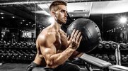 Focused young muscular man performing a full body medicine ball workout