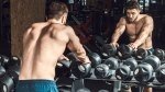 Muscular fitness model looking in the mirror next to the dumbbell rack performing a Advanced Training Techniques