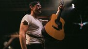 Chase Rice performing on stage with an acustic guitar