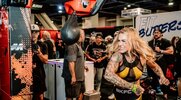 Female bodybuilder Whitney Cummings punching an arcade punching bag at the Olympia 2024 Expo