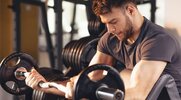 bearded man doing bicep workout with preacher curl