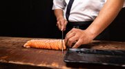 Sushi chef holding a fresh piece of salmon preparing it for omakase