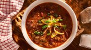 Canned chili served in a bowl with shredded cheese