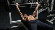 Lean and toned muscular man performing a benchpress using the Priming training technique for stronger muscles