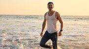 Actor Luke Cook wearing a wet tank top while on the beach