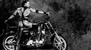 ring-leather-chaps-and-posing-next-to-a-motorcycle.webp