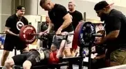 -performing-a-heavy-load-bench-press-with-spotters.webp