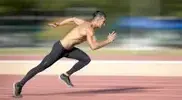 Muscular man doing HIIT sprinting workouts by sprinting on a running track