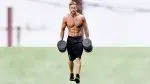 Male fitness model with a muscular core doing forearm workouts with dumbbell farmer's carry exercise