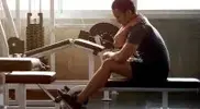 Young male working out in the gym with a shoulder injury and recovering with the muscle flossing technique due to muscle soreness