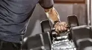 Man lifting a heavy single dumbbell off the dumbbell rack