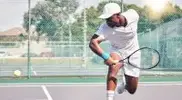 Tennis player returning a serve with a backhand shot