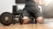 Man wrapping his hands for a home workout with dumbbells and to develop his power