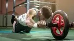 Man working out with an ab wheel rollout exercise in the gym