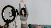 Fitness influencer stretching in front of her phone and ring light