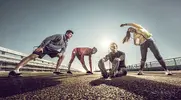 A group of fit people doing warm up exercises outdoors before a workout