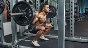 Fitness model doing a barbell back squat exercise