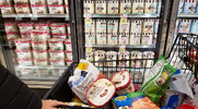 Person grocery shopping in the ice cream aisle for the healthiest ice creams