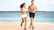 Fit couple running on the shoreline of a beach