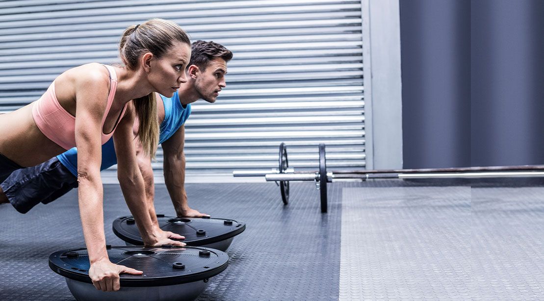 Couple performing bosu ball exercises and building musclees